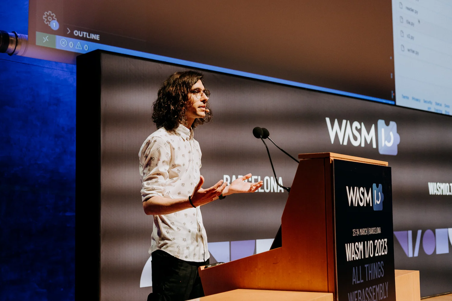 Me talking about Wasm Workers Server at Wasm IO. I'm wearing a white shirt and I have Visual studio code in the background